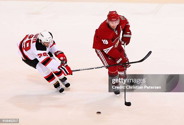 Shane Doan of the Phoenix Coyotes handles the puck under pressure from Vladimir Zharkov of the New Jersey Devils during the NHL game at Jobing.com...