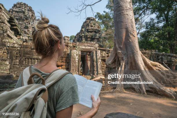 jeune femme lisant guidebook à temple antique au cambodge - guide touristique photos et images de collection