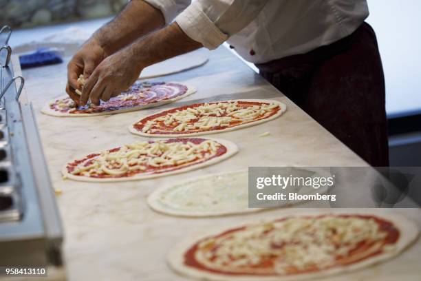 An employee adds toppings to pizza bases inside a Vapiano SE Italian themed cuisine restaurant in Cologne, Germany, on Monday, May 14, 2018. One of...
