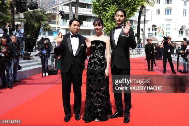 Japanese director Ryusuke Hamaguchi, Japanese actress Erika Karata and Japanese actor Masahiro Higashide wave as they arrive on May 14, 2018 for the...