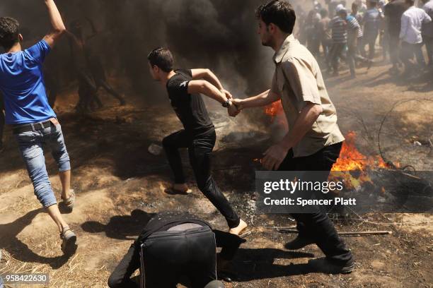 Palestinians rush to the border fence with Israel as mass demonstrations at the fence continue on May 14, 2018 in Gaza City, Gaza. Israeli soldiers...