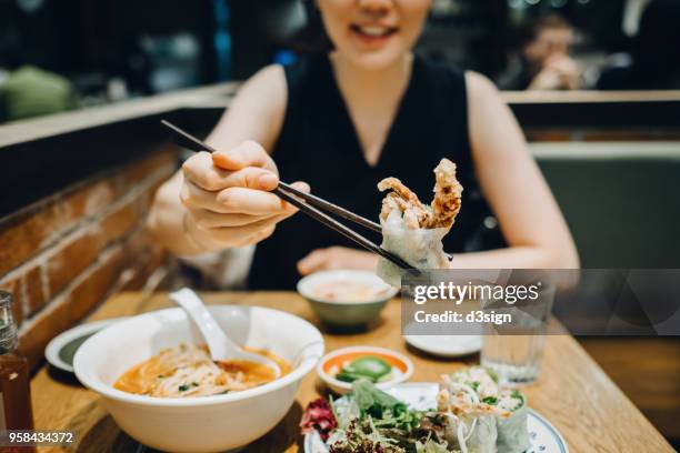 smiling asian woman enjoying fresh vietnamese cuisine in restaurant - vietnamese cuisine stock pictures, royalty-free photos & images