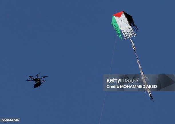 An Israeli army drone flies near a Palestinian kite along the border between Israel and the Gaza Strip, east of Gaza City on May 14, 2018....