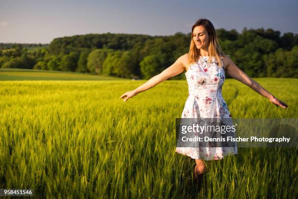 woman enjoys sunset in field - sparse foto e immagini stock