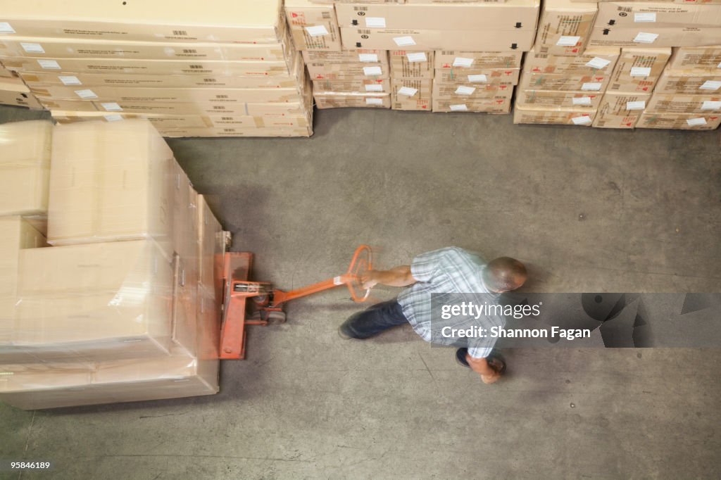 Man pulling pallet with stack of boxes