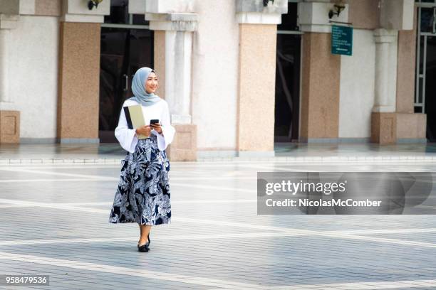 female muslim college student walking on campus full length - malaysian culture stock pictures, royalty-free photos & images
