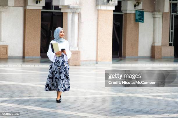 female muslim college student walking on campus full length - malaysia culture stock pictures, royalty-free photos & images