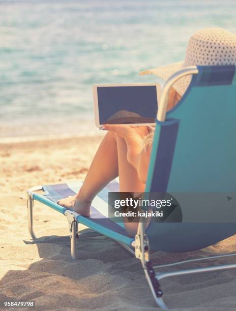 young woman relaxing at the beach - chaise longue stock pictures, royalty-free photos & images