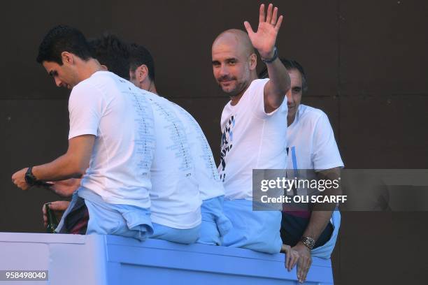 Manchester City's Spanish manager Pep Guardiola waves from atop a bus as the Manchester City team take part in an open-top bus parade through...