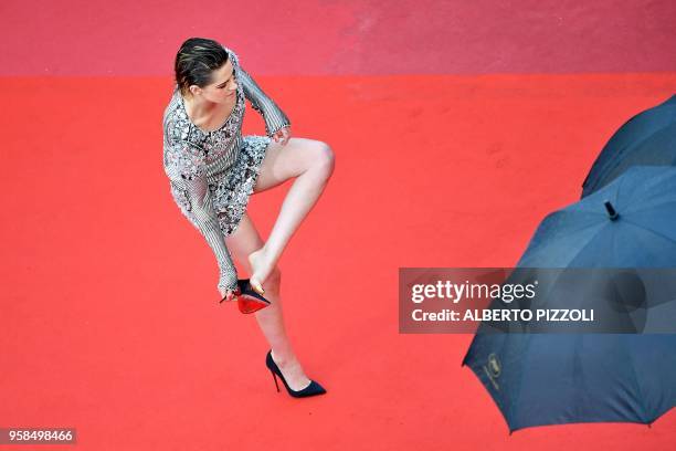 Actress and member of the Feature Film Jury Kristen Stewart removes her shoes on the red carpet as she arrives on May 14, 2018 for the screening of...