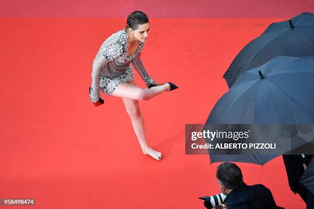 Actress and member of the Feature Film Jury Kristen Stewart removes her shoes on the red carpet as she arrives on May 14, 2018 for the screening of...