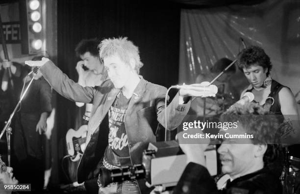 Julien Temple films in the foreground as Sid Vicious , Johnny Rotten and Steve Jones of British punk band the Sex Pistols perform on stage at a free...
