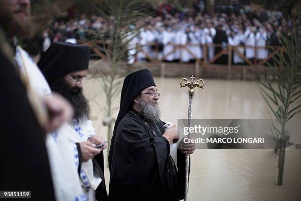 Christian Orthodox worshippers gather on the Jordanian side of the Jordan River while an Orthodox priest holds a white dove about to be freed from...