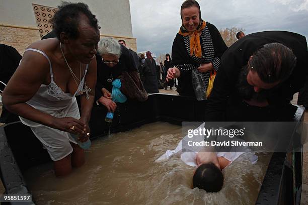 An Orthodox Christian priest baptizes pilgrims in a tub of water drawn from the River Jordan on January 18, 2010 at the Qasr al Yahud baptism site...