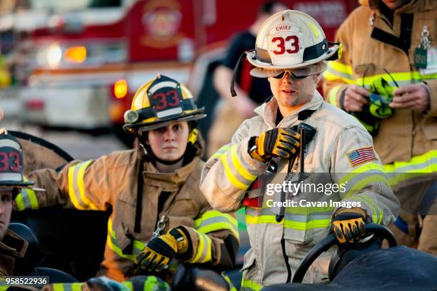 firefighter holding walkie-talkie while standing by coworkers - rescue services occupation stock pictures, royalty-free photos & images