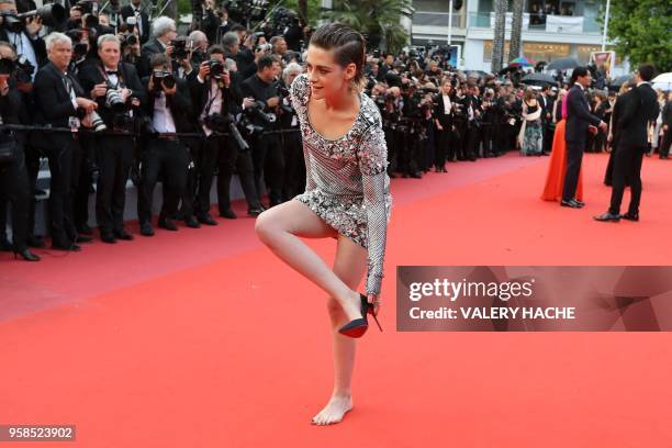 Actress and member of the Feature Film Jury Kristen Stewart removes her shoes on the red carpet as she arrives on May 14, 2018 for the screening of...