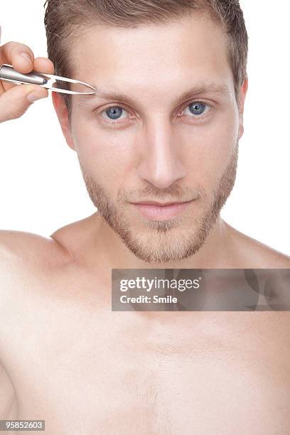 young man plucking his eyebrows - man plucking eyebrows stock pictures, royalty-free photos & images