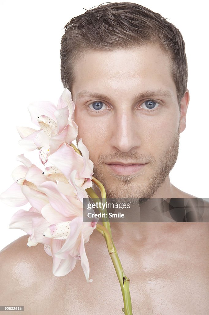 Young man with orchid against his cheek