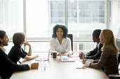 Smiling african american female boss leading corporate diverse team meeting
