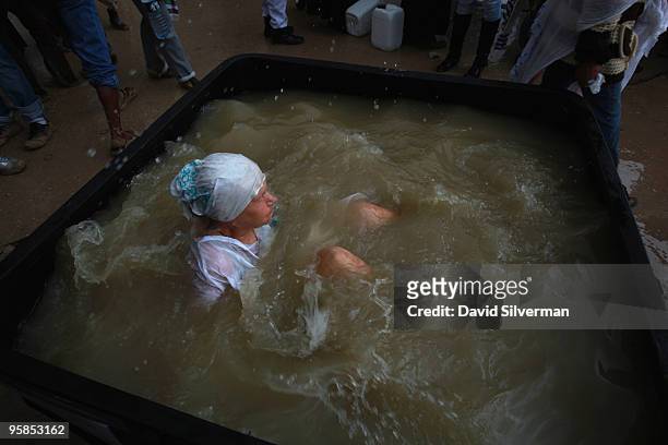 Christian pilgrim baptizes herself in a tub of water drawn from the River Jordan on January 18, 2010 at the Qasr al Yahud baptism site near Jericho...