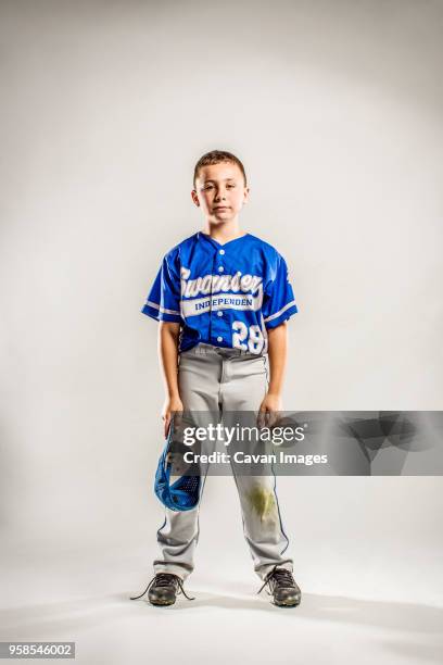 portrait of baseball player with cap in hand against white background - honkbaltenue stockfoto's en -beelden