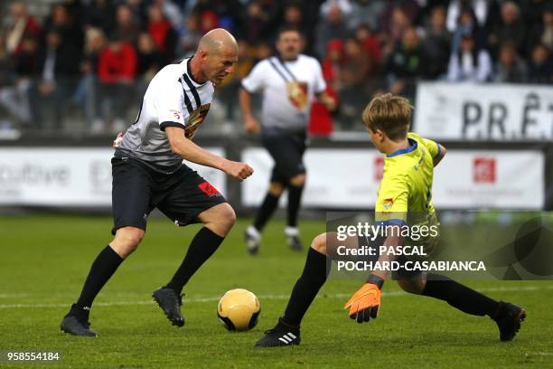 Real Madrid's French coach Zinedine Zidane vies with Lisandru Olmeta during the charity match organized by French football player Pascal Olmeta for...