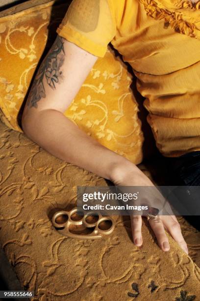 cropped image of woman with brass knuckle sitting on sofa - knuckle duster imagens e fotografias de stock