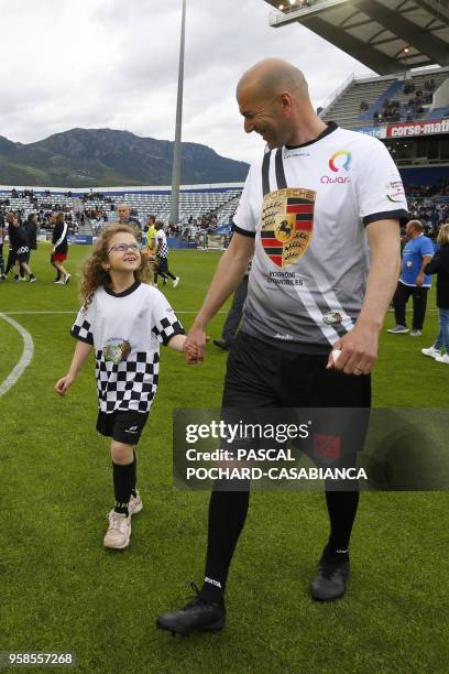 Real Madrid's French coach Zinedine Zidane arrives with a child before the start of the charity match organized by French football player Pascal...