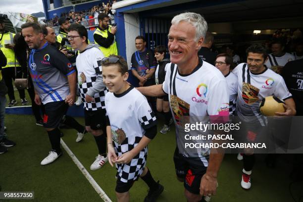 France's coach Didier Deschamps walks on the pitch with a child before the start of the charity match organized by French football player Pascal...