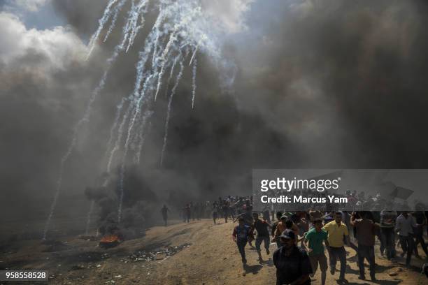 Protesters run away from tear gas dispersed by Israeli forces as they inch closer to the border fence separating Israel and Gaza on May 14, 2018 in a...
