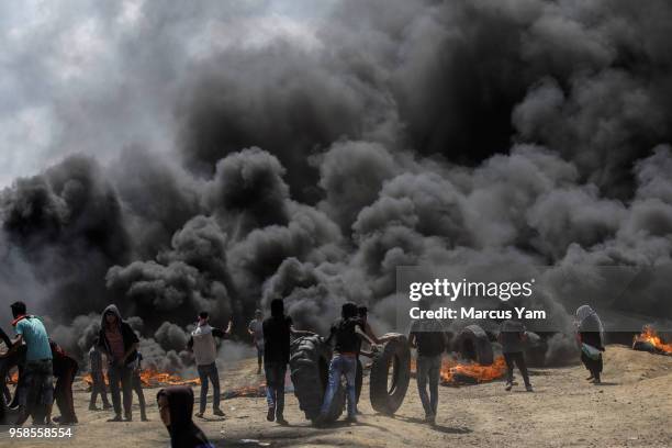 Palestinians burn tires to create a smoke column meant to reduce visibility for Israeli forces at the border fence separating Israel and Gaza on May...