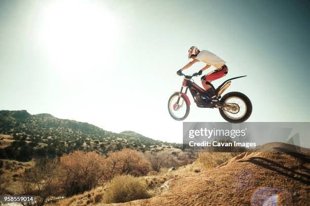 side view of man performing stunt with motorcycle against clear sky - motocross stock photos et images de collection