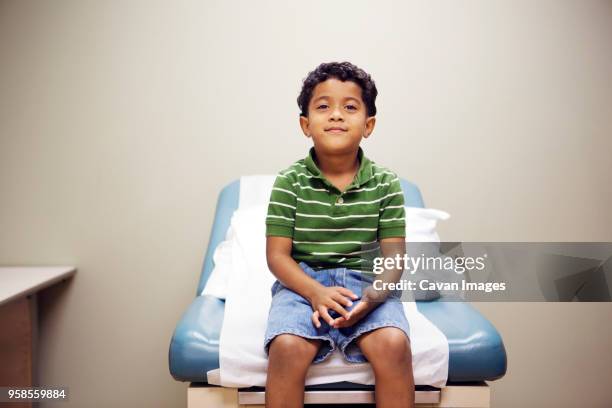 portrait of boy sitting on bed in hospital - tavolo da visita foto e immagini stock