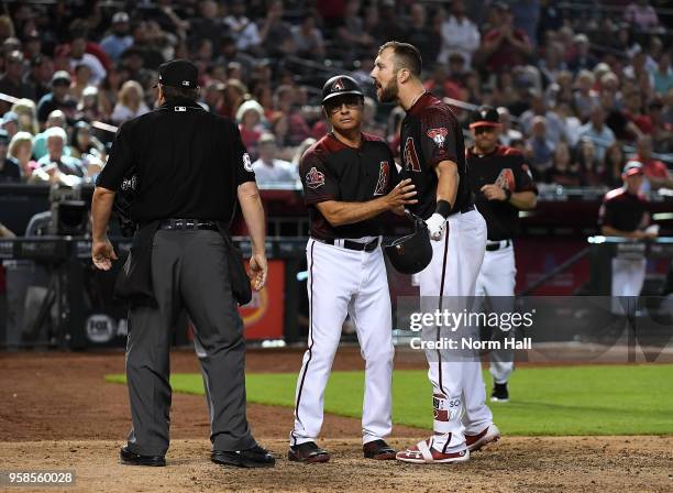 Steven Souza Jr of the Arizona Diamondbacks is held back by third base coach Tony Perezchica while arguing with home plate umpire Doug Eddings after...