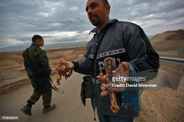 An Israeli army officer passes a Palestinian vendor selling religious souvenirs during Epiphany celebrations on January 18, 2010 at the Qasr al Yahud...