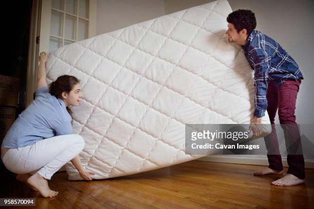 couple carrying mattress in room - new boyfriend stock pictures, royalty-free photos & images