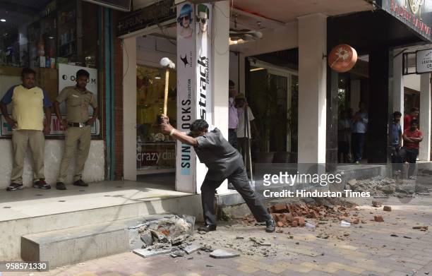 Workers remove encroachment from the footpath during the anti-encroachment drive at Mehar Chand Market, Lodhi Road on May 14, 2018 in New Delhi,...