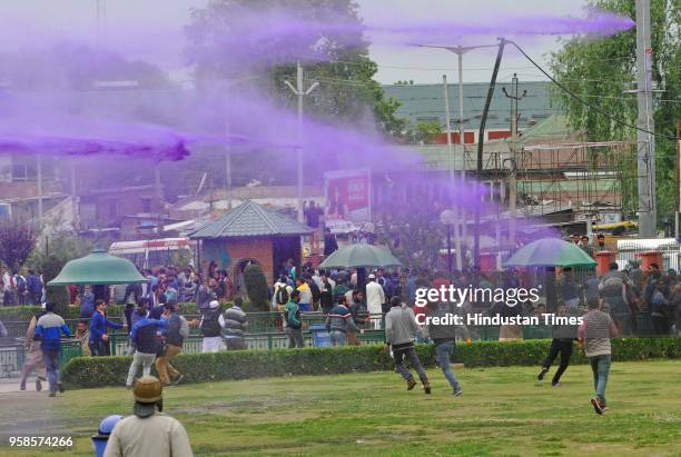 Government teachers of Kashmir run for cover as police spray purple colored water from a water canon to disperse them, during a protest on May 14,...