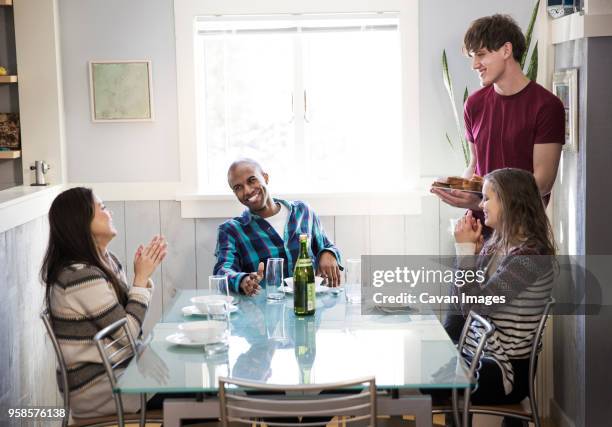 happy friends by dining table at home - man leaning chair standing side view stock pictures, royalty-free photos & images