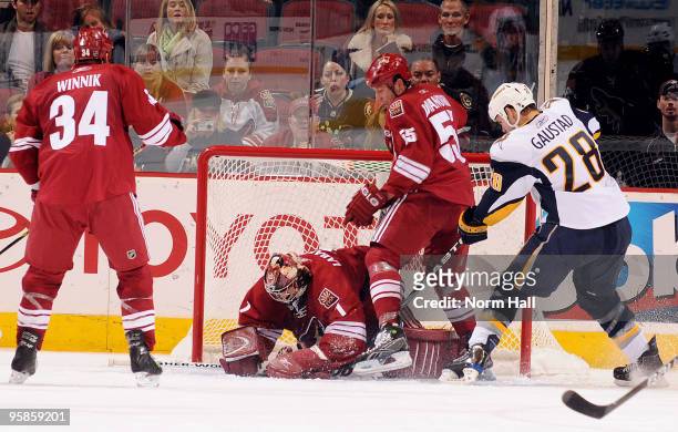 Jason La Barbera of the Phoenix Coyotes covers the puck while Ed Jovanovski stops Paul Gaustad of the Buffalo Sabres from getting a rebound on...