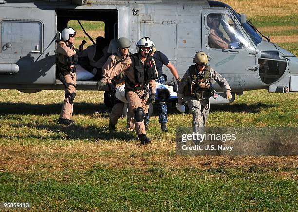 In this handout image provided by the U.S. Navy, U.S. Military servicemen transport a patient from an SH-60F Sea Hawk helicopter assigned to the...