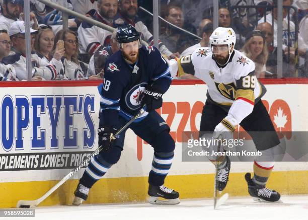 Bryan Little of the Winnipeg Jets plays the puck along the boards as Alex Tuch of the Vegas Golden Knights defends during first period action in Game...