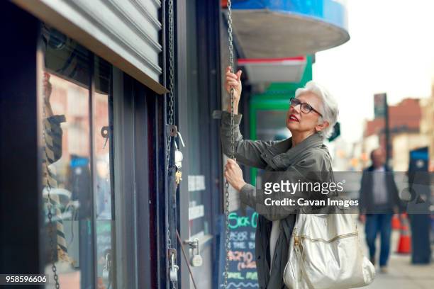 woman opening store shutter - bolso abierto fotografías e imágenes de stock