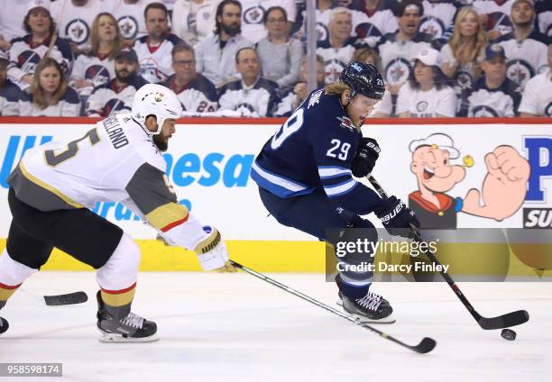 Patrik Laine of the Winnipeg Jets plays the puck down the ice as Deryk Engelland of the Vegas Golden Knights gives chase during first period action...