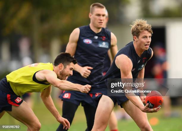 Mitch Hannan of the Demons handballs whilst being tackled by Alex Neal-Bullen during a Melbourne Demons AFL training session at Gosch's Paddock on...