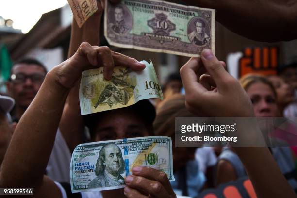 Attendees hold a replica 100 U.S. Dollar banknotes, used as campaign literature, and Venezuelan Bolivar banknotes during a campaign rally for Henri...