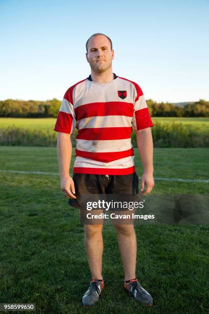 full length portrait of rugby player standing on grassy field - rugby shorts stock-fotos und bilder