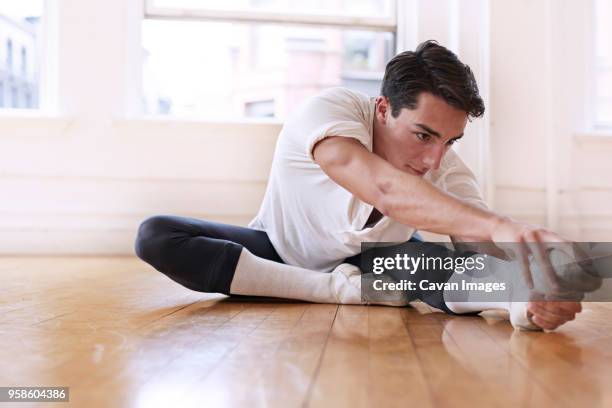 determined male ballet teacher exercising on floor at studio - pies bailando fotografías e imágenes de stock