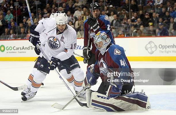 Goalie Craig Anderson of the Colorado Avalanche collects the puck and makes a save as Ethan Moreau of the Edmonton Oilers looks for a rebound during...