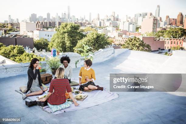 happy friends enjoying food on building terrace - topfpflanze stock-fotos und bilder